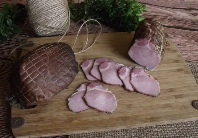 Jak zrobić soczysty schab wędzony? Na desce leżą dwa wędzone kawałki schabu, jeden w całości, drugi pokrojony w plastry.