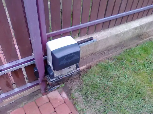 Silnik bramy przesuwnej, która po zamknięciu sama się otwiera, z widocznym zębatką i mechanizmem.