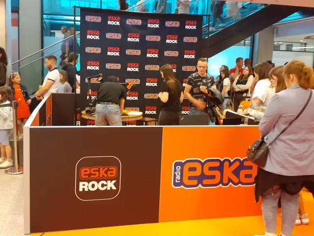Stoisko radiowe Eska Rock z ludźmi i logo stacji.