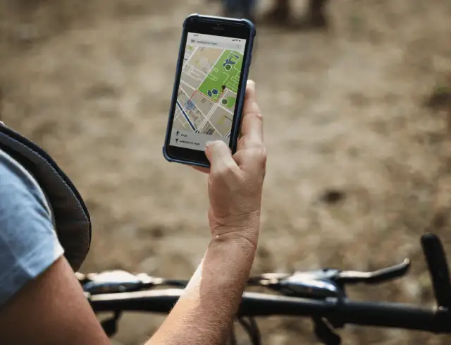 Rowerzysta sprawdza na telefonie mapę z trasą. Lokalizator GPS do roweru pomaga znaleźć drogę.