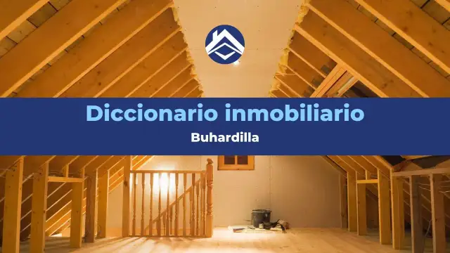 Interior de una buhardilla en construcción, con vigas de madera expuestas y una escalera. El texto indica "Diccionario inmobiliario: Buhardilla".