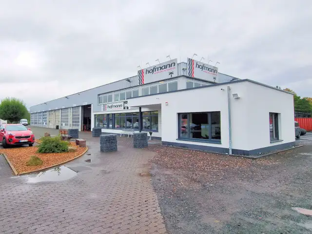 Gebäude von Reifen Hofmann Bebra mit roten Auto davor.
