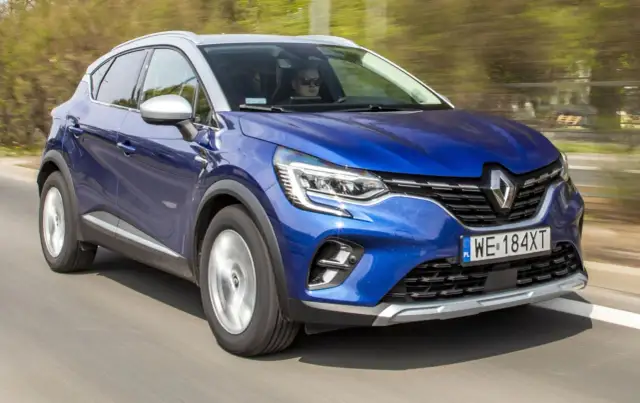 Błękitny Renault Captur 2019 pędzi po drodze, kierowca w okularach obserwuje trasę.