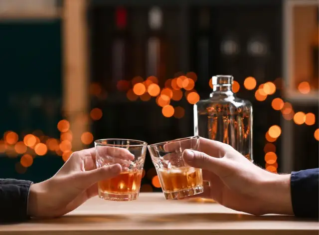 Dwie osoby wznoszą toast whisky. Zastanawiasz się, ile cukru jest w whisky?