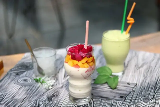 Trzy koktajle: jeden z owocami smoczego, mango i kremem, drugi zielony, trzeci z lodem.
