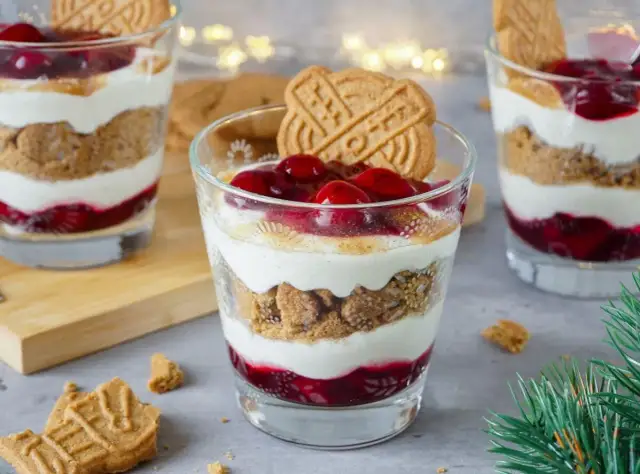 Festliche Desserts im Glas mit Kirschen, Kekskrümeln und Sahne, garniert mit Spekulatius.