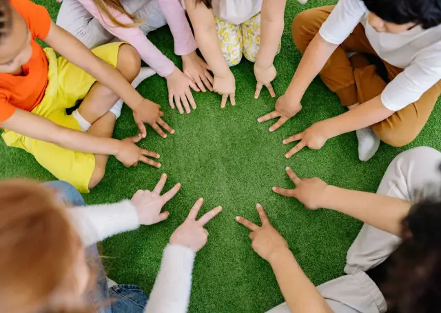 Dzieci tworzą krąg, pokazując palcami cyfry. To spokojne zabawy wyciszające Montessori, rozwijające koncentrację i współpracę.
