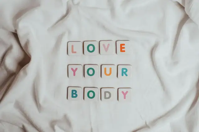 Kolorowe kafelki z literami układają się w napis "LOVE YOUR BODY". To piękna afirmacja, która przypomina o akceptacji siebie.