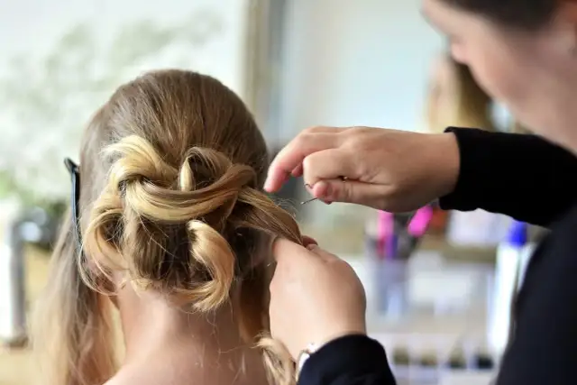 Fryzjerka tworzy elegancką fryzurę ślubną. Jej praca to sztuka, a kod zawodu fryzjer to opis jej talentu.