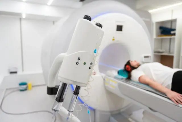 Pacjentka leży w skanerze MRI, z przodu widoczny element aparatu z wtryskiwaczami.