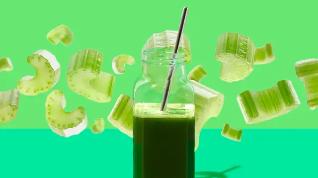 Ein Glas Selleriesaft mit einem Strohhalm, umgeben von schwebenden Selleriestücken. Die Selleriesaft Wirkung wird hier visuell dargestellt.