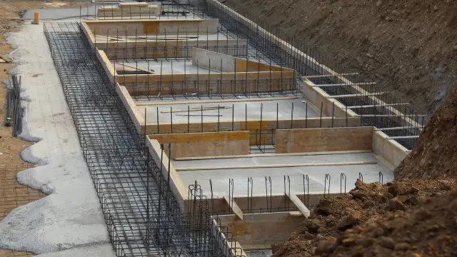 Szkielet zbrojeniowy i szalunki drewniane czekają na beton. Tak wygląda budowa fundamentów krok po kroku.