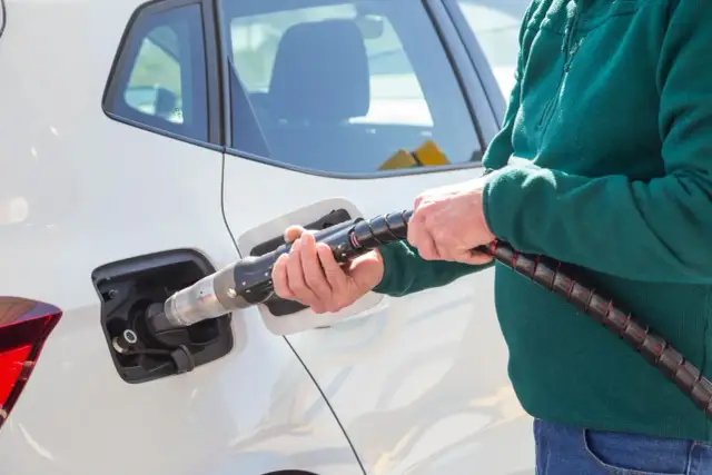 Tankowanie samochodu CNG i hybryda: co to za paliwo? Dłoń trzyma pistolet do tankowania gazu ziemnego.