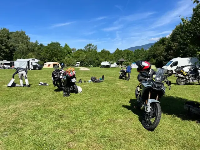 Motocykle zaparkowane na kempingu, w tle namioty i kampery.