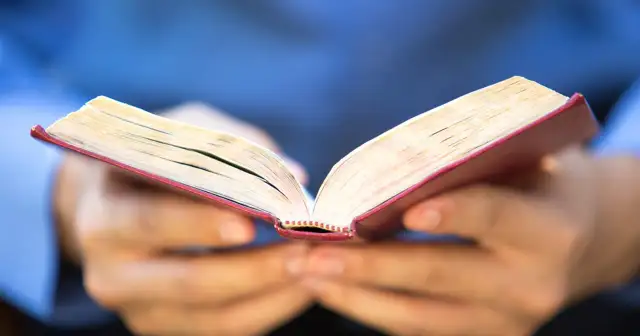 Otwarta księga w dłoniach, strony pełne mądrości. Czytanie to droga do poznania, jak 5 przykazanie.