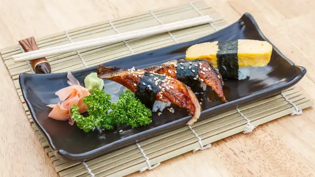 Sushi z węgorzem w sosie unagi. Co to za pyszny sos? Na talerzu też tamago, wasabi i marynowany imbir.