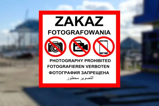 Znak ZAKAZ FOTOGRAFOWANIA z ikonami aparatu, kamery i telefonu komórkowego w czerwonych okręgach.