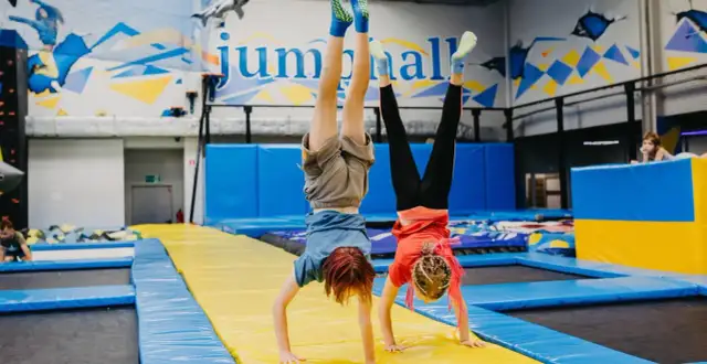 Dzieci robią stanie na rękach na trampolinach w sali gimnastycznej.