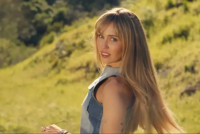 Miley Cyrus w nowej piosence, w letniej stylizacji, na tle zielonych wzgórz.
