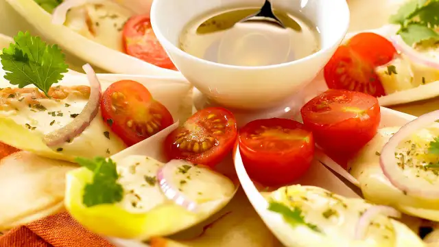 Chicorée-Schiffchen gefüllt mit cremigem Salat, garniert mit Kirschtomaten und roten Zwiebelringen. Ein leichter und frischer Chicorée-Birnen-Salat.