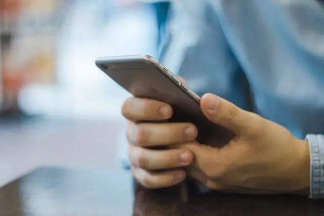 Dłonie trzymające smartfon, szukające inspiracji, jak zacząć rozmowę na Badoo.
