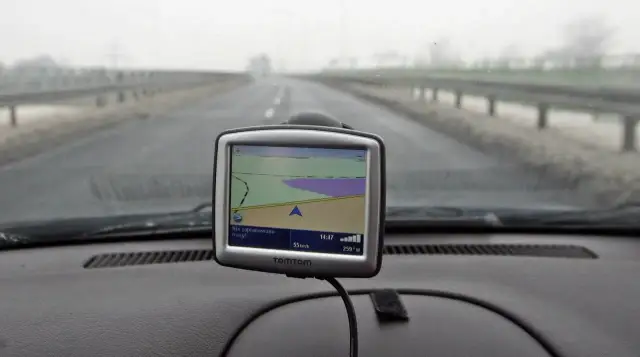 Nawigacja TomTom na desce rozdzielczej samochodu podczas jazdy w mglisty dzień.