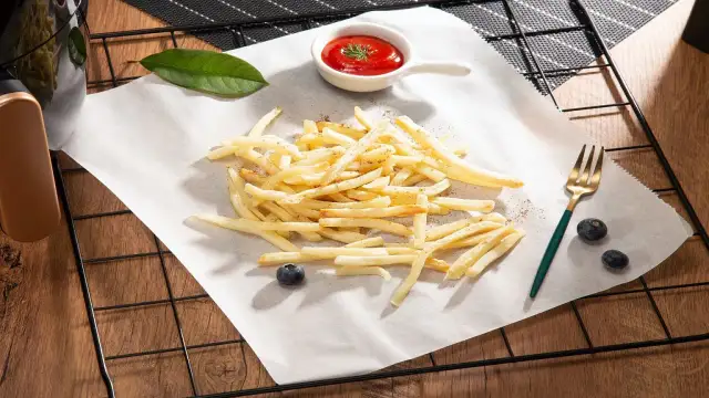 Chrupiące frytki z piekarnika na papierze do pieczenia, z ketchupem i borówkami.