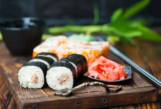 Pyszne sushi z kremowym nadzieniem, obok marynowany imbir i miseczka na sos do sushi.