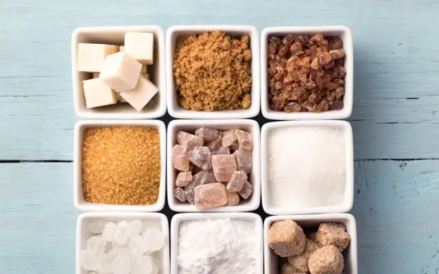 Neuf carrés blancs remplis de différents types de sucre : cubes blancs, cassonade, sucre candi, etc.