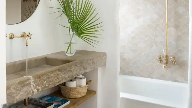 Elegante lavabo de piedra natural y grifería dorada, parte de una cuidada decoracion cuartos de baño con azulejos de escamas.