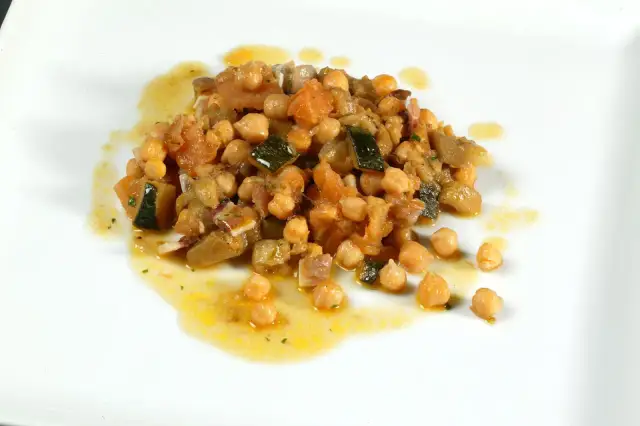 Deliciosos garbanzos con pisto, una mezcla colorida de verduras y legumbres en un plato blanco.