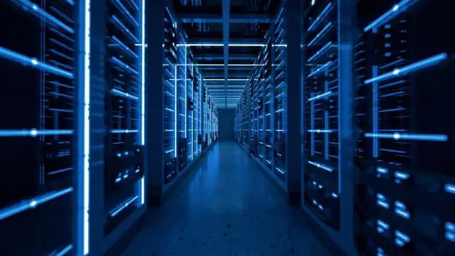 Wnętrze nowoczesnego data center z rzędami serwerów oświetlonych niebieskim światłem.