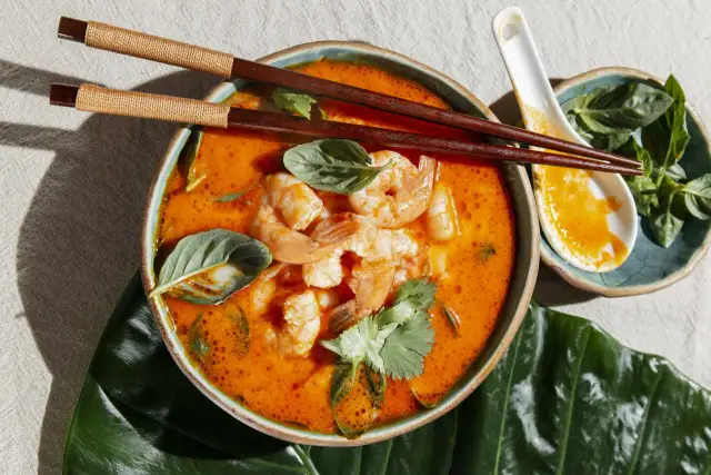 Aksamitny, pomarańczowy bulion z krewetkami i ziołami, idealny do jedzenia pałeczkami. To pyszne danie to klasyczne **pasta tom yum**.
