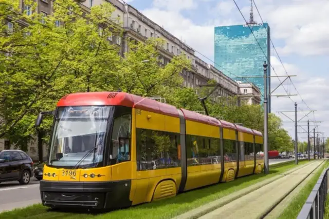 Żółto-czerwony tramwaj na zielonym torowisku. Zastanawiasz się, ile zarabia kierowca tramwaju?