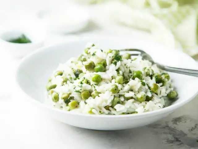 Pyszny ryż z groszkiem i ziołami, podany w białej misce, gotowy do zjedzenia.