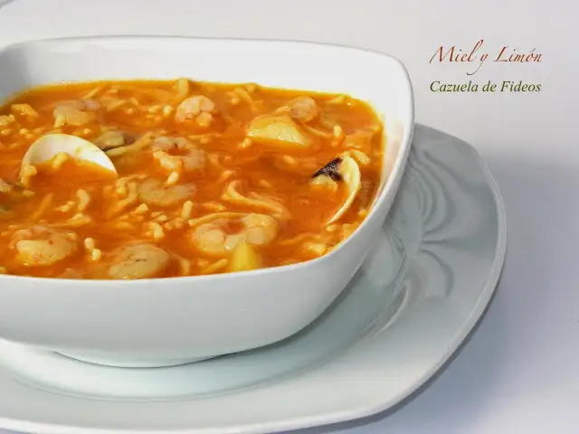 Cazuela de fideos con gambas y mejillones en un cuenco blanco.