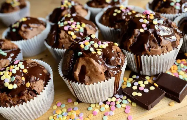 Czekoladowe muffiny polane lukrem i posypane kolorową posypką. Proste sposoby, jak dekorować muffiny, by wyglądały apetycznie.