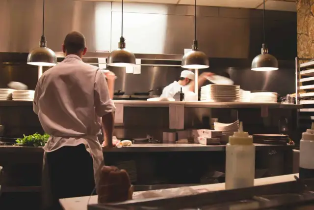 Kucharz w białej koszuli i fartuchu pracuje w kuchni restauracyjnej. To idealne miejsce, by napisać list motywacyjny kucharz.