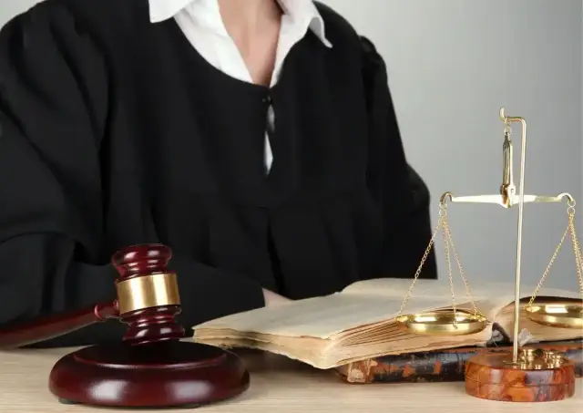 Sąd w todze, młotek sędziowski, waga sprawiedliwości i księgi prawne.