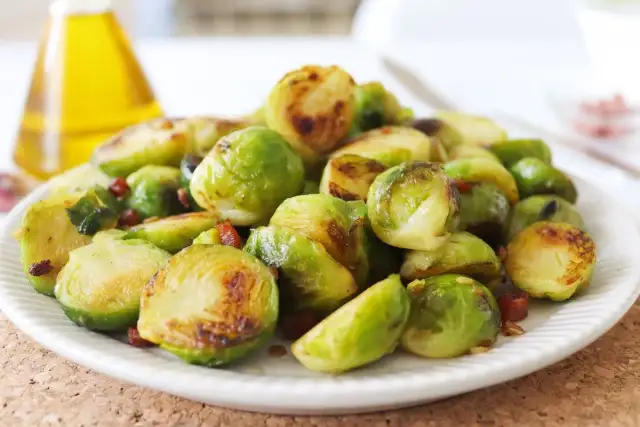 Plato de coles de Bruselas al horno, doradas y tiernas, con trocitos de bacon crujiente. Un manjar irresistible.