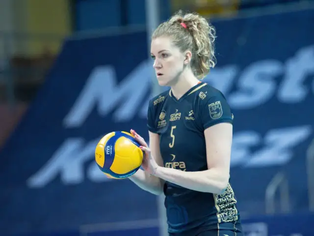 Agnieszka Korneluk, siatkarka z numerem 5, trzyma piłkę. Jej mąż pewnie kibicuje jej z trybun.