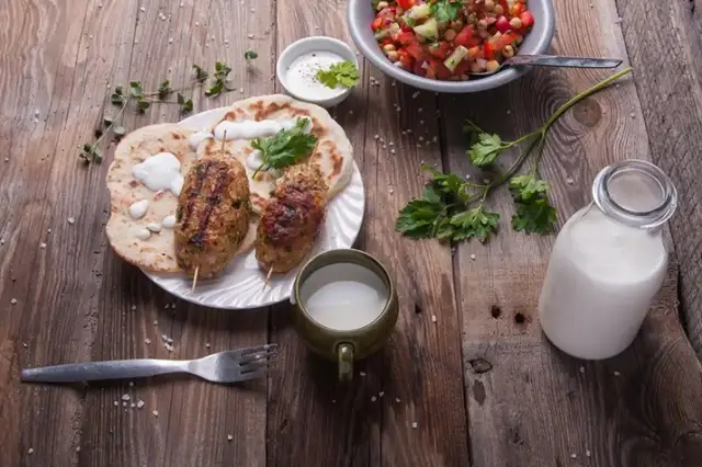 Kebab z płaskim chlebem, sałatką i napojem. Czy to ayran? To orzeźwiający napój jogurtowy, idealny do takiego posiłku.