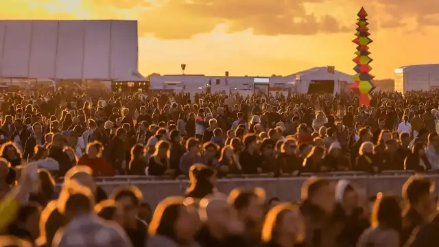Tłum ludzi na festiwalu, zachód słońca. Kolorowa instalacja artystyczna w tle. Kto będzie następny na scenie?