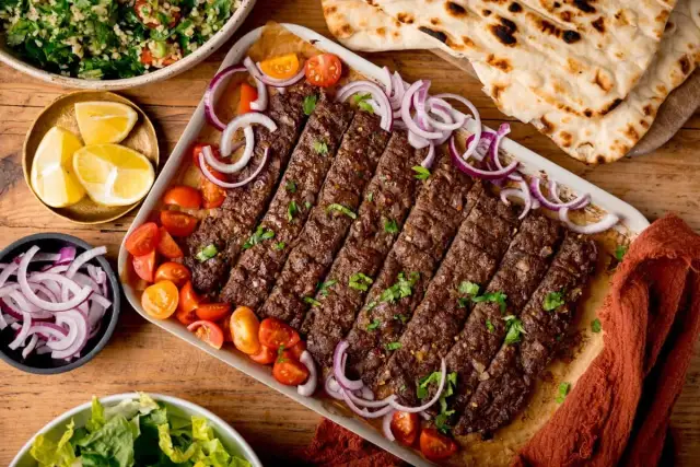 Kebab z mięsa mielonego, pomidorkami, cebulą i pieczywem.
