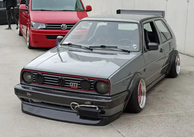 Szary, zmodyfikowany Volkswagen Golf GTI z szerokimi błotnikami i spojlerem.
