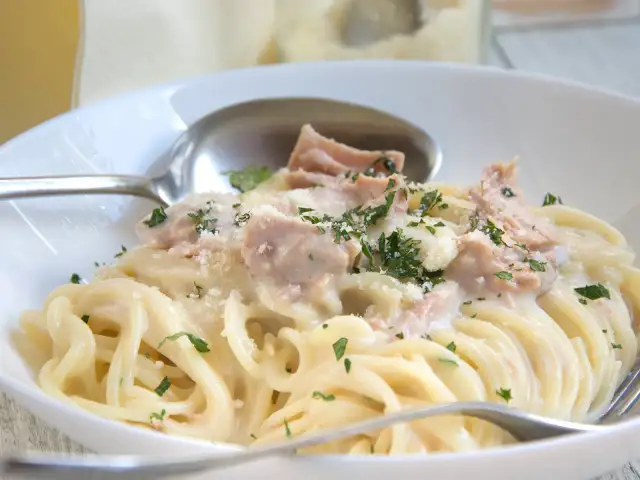 Cremige Nudeln mit Thunfisch, garniert mit Petersilie und Parmesan. Ein köstliches Gericht, das Lust auf mehr macht.