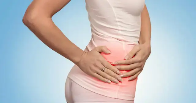 Kobieta trzyma się za bolące talerze biodrowe, zaznaczone czerwonym rumieńcem.