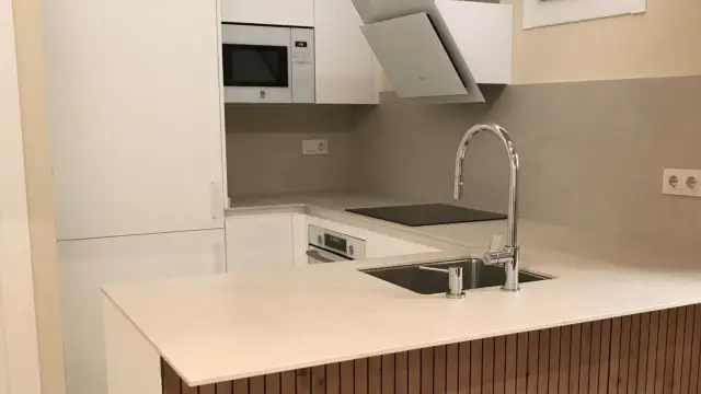 Cocinas pequeñas modernas con electrodomésticos integrados, encimera clara y grifería cromada.