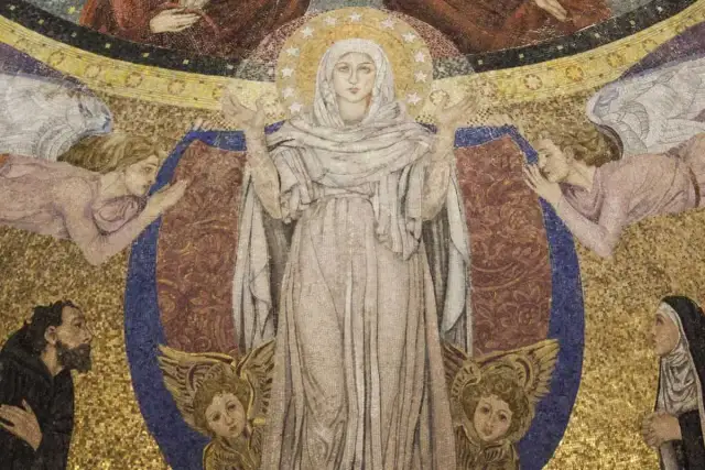 Wielobarwna mozaika przedstawia Matkę Boską otoczoną przez anioły i wiernych, symbolizującą kult maryjny.