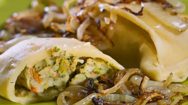 Maultaschen low carb gefüllt mit Gemüse, serviert mit karamellisierten Zwiebeln auf einem grünen Teller.